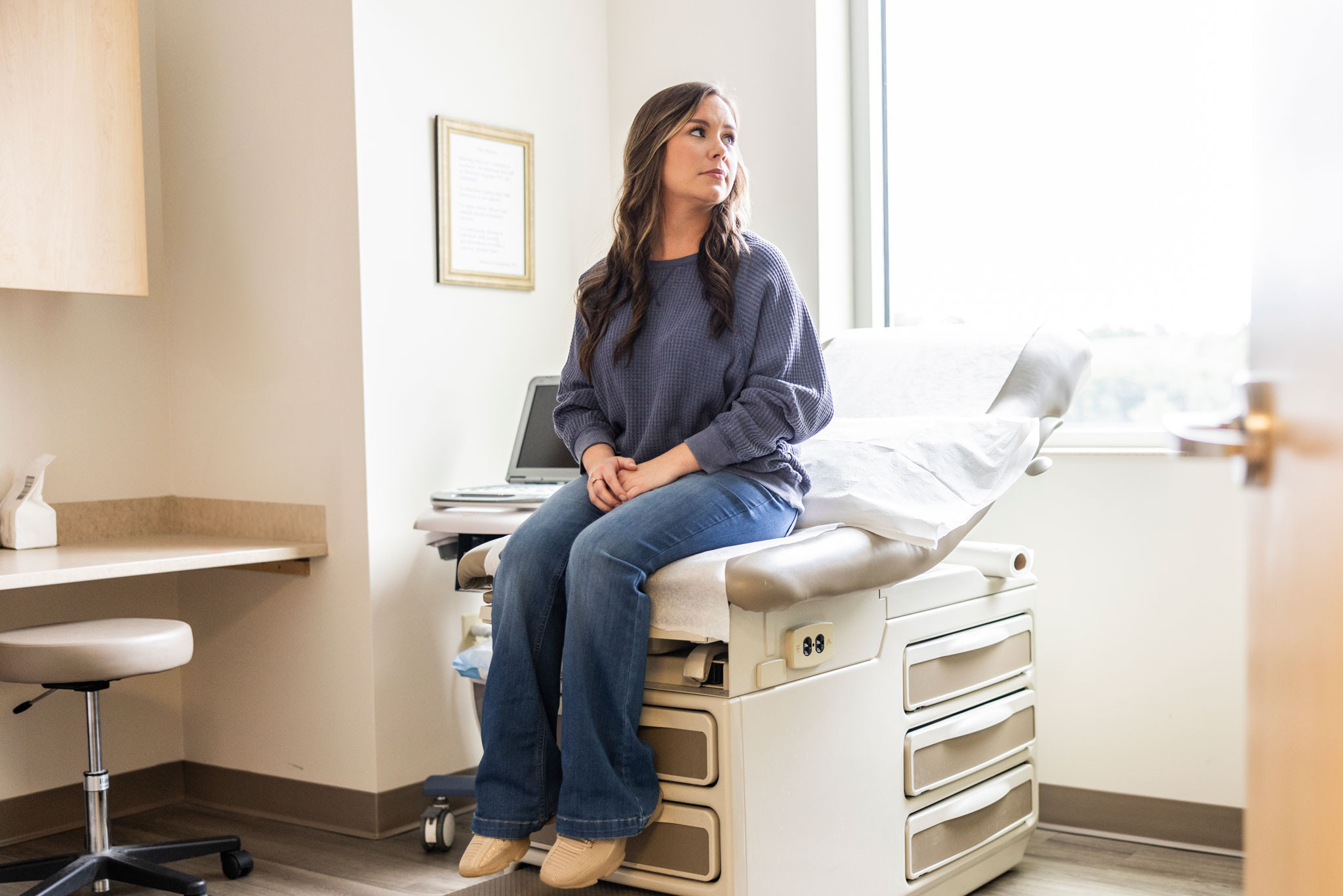 Young Female Patient Waiting In Doctor's Exam Room